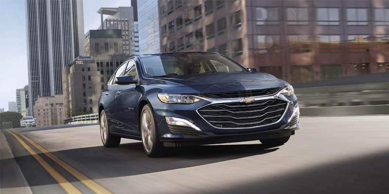Malibu Vehicle Moving on a Road in Front of a Building